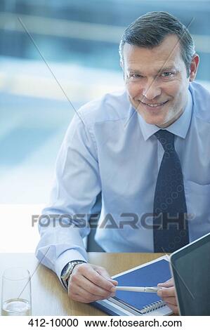 Stock Image - Businessman smiling at desk. Fotosearch