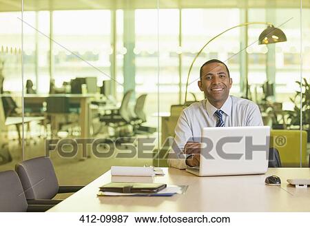 Businessman smiling at desk View Large Photo Image Stock Photo - Businessman smiling at desk. Fotosearch