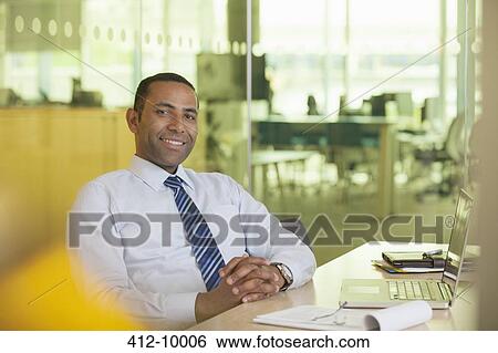 Stock Photograph - Businessman smiling at desk. Fotosearch