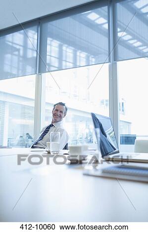 Stock Image - Businessman smiling in conference room. Fotosearch