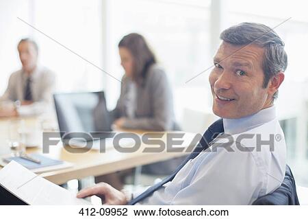 Stock Image - Businessman smiling in office. Fotosearch