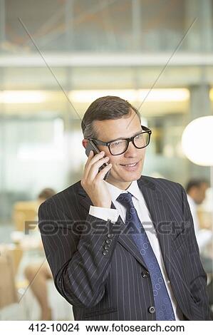 Businessman talking on cell phone in office View Large Photo Image Picture - Businessman talking on cell phone in office. Fotosearch