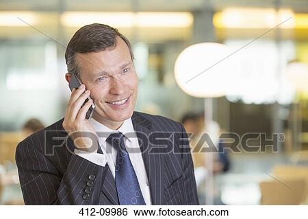 Businessman talking on cell phone in office View Large Photo Image Stock Photograph - Businessman talking on cell phone in office. Fotosearch