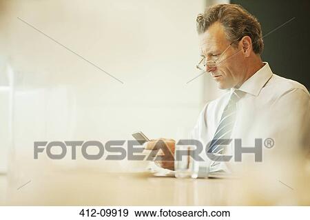 Stock Photo - Businessman using cell phone in cafe. Fotosearch
