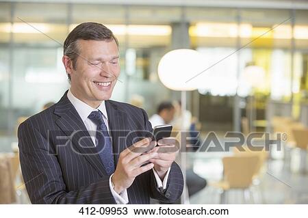 Businessman using cell phone in office View Large Photo Image Stock Image - Businessman using cell phone in office. Fotosearch