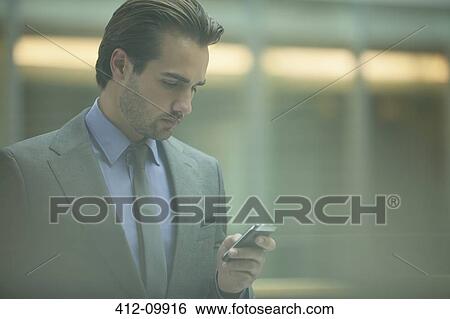Businessman using cell phone in office View Large Photo Image Stock Photograph - Businessman using cell phone in office. Fotosearch