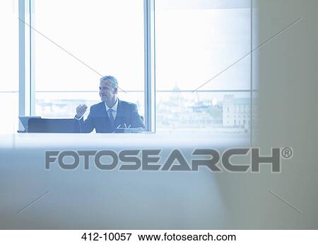Businessman working at desk in office View Large Photo Image Stock Photo - Businessman working at desk in office. Fotosearch