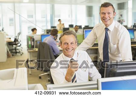 Stock Image - Businessmen smiling in office. Fotosearch