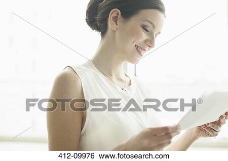 Businesswoman reading papers in office View Large Photo Image Stock Photograph - Businesswoman reading papers in office. Fotosearch
