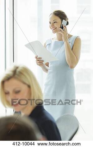 Businesswoman talking on cell phone in office View Large Photo Image Picture - Businesswoman talking on cell phone in office. Fotosearch