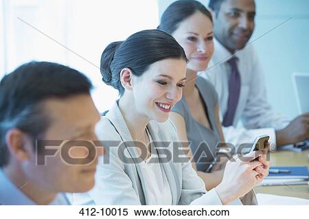 Businesswoman using cell phone in meeting View Large Photo Image Stock Photography - Businesswoman using cell phone in meeting. Fotosearch