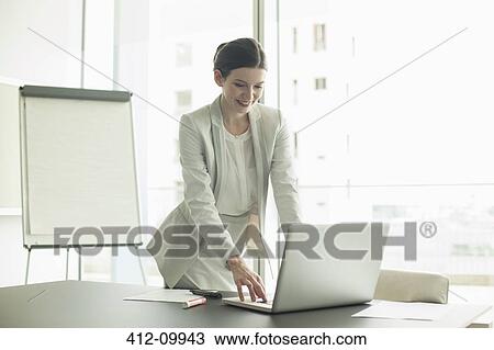 Stock Image - Businesswoman using laptop in office. Fotosearch