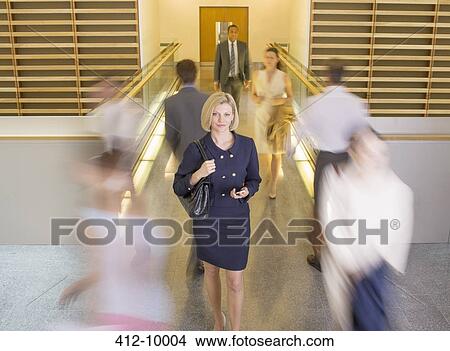 Businesswoman walking in busy office corridor View Large Photo Image Picture - Businesswoman walking in busy office corridor. Fotosearch
