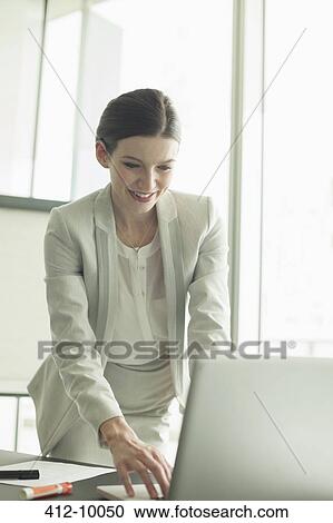 Businesswoman working at laptop in office View Large Photo Image Stock Image - Businesswoman working at laptop in office. Fotosearch