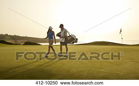 Caddy and woman walking on golf course overlooking ocean View Large Photo Image Stock Image - Caddy and woman walking on golf course overlooking ocean. Fotosearch