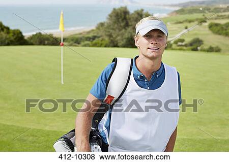 Stock Photo - Caddy smiling on golf course. Fotosearch