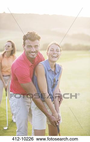 Stock Photograph - Couple playing golf on course. Fotosearch