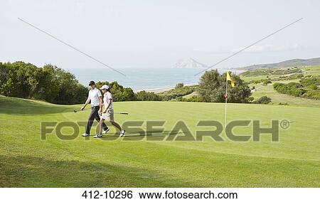 Stock Photograph - Couple walking on golf course. Fotosearch