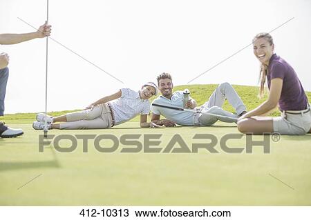 Friends laying on golf course View Large Photo Image Stock Image - Friends laying on golf course. Fotosearch