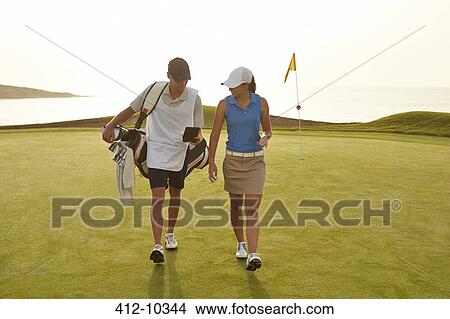 Golfer and caddy walking on golf course View Large Photo Image Picture - Golfer and caddy walking on golf course. Fotosearch