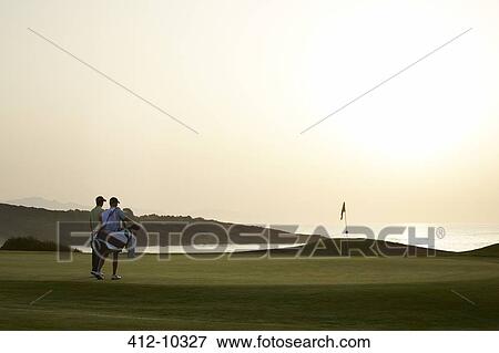 Men on golf course at sunset View Large Photo Image Stock Photo - Men on golf course at sunset. Fotosearch