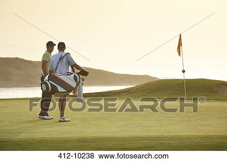 Stock Photo - Men on golf course overlooking ocean. Fotosearch