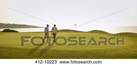 Stock Image - Men walking on golf course. Fotosearch
