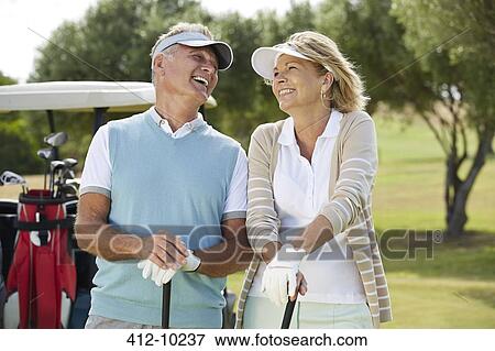Stock Photo - Senior couple laughing on golf course. Fotosearch