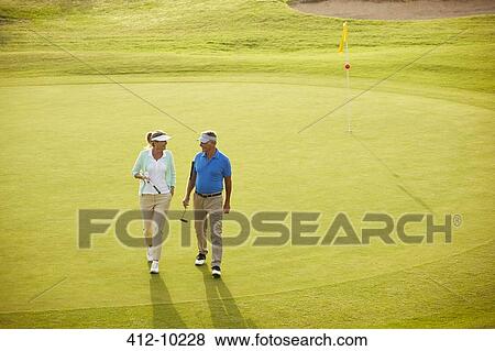 Stock Photo - Senior couple walking on golf course. Fotosearch