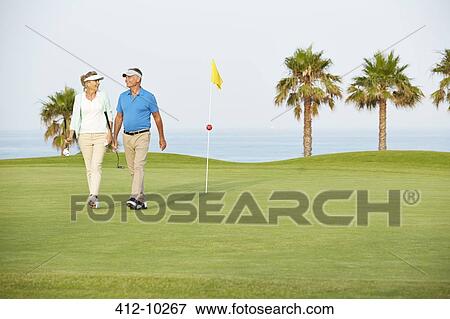 Senior couple walking on golf course View Large Photo Image Stock Photo - Senior couple walking on golf course. Fotosearch