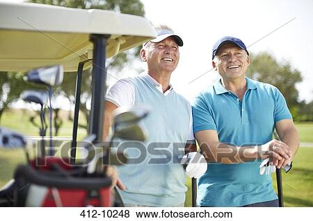 Senior man standing next to golf cart View Large Photo Image Stock Photo - Senior man standing next to golf cart. Fotosearch