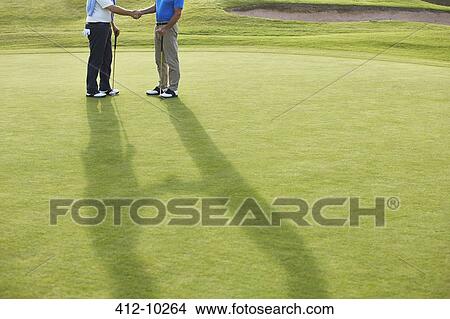 Picture - Senior men shaking hands on golf course. Fotosearch