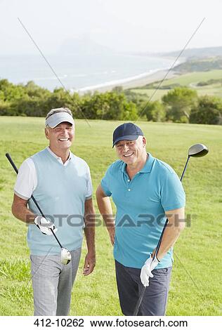 Stock Image - Senior men smiling on golf course overlooking ocean. Fotosearch