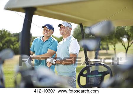 Stock Photo - Senior men standing next to golf cart. Fotosearch