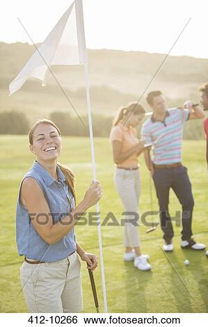 Stock Photograph - Smiling woman holding golf flag. Fotosearch