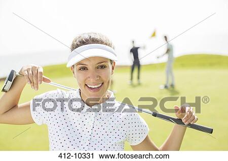 Stock Image - Woman holding golf club. Fotosearch