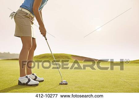Stock Photo - Woman putting on golf course. Fotosearch