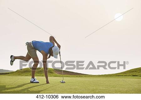 Woman reaching for ball in hole on golf course View Large Photo Image Stock Photograph - Woman reaching for ball in hole on golf course. Fotosearch