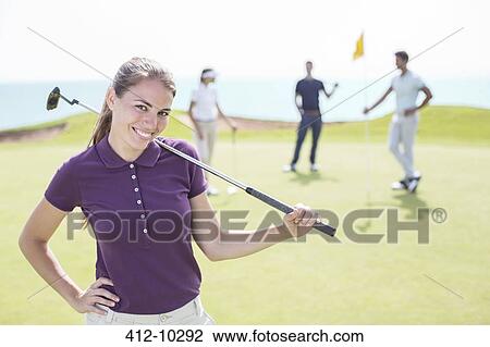 Stock Image - Woman smiling on golf course. Fotosearch