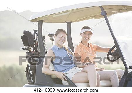 Stock Photo - Women driving golf cart on course. Fotosearch