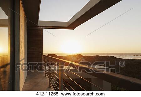 Stock Photography - Balcony of modern house overlooking ocean at sunset. Fotosearch