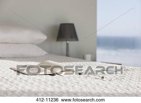 Book and glasses on bed in modern bedroom with ocean view View Large Photo Image Stock Photograph - Book and glasses on bed in modern bedroom with ocean view. Fotosearch