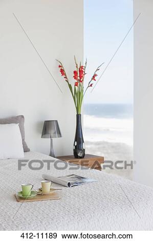 Stock Photo - Breakfast tray on bed in modern bedroom with ocean view. Fotosearch