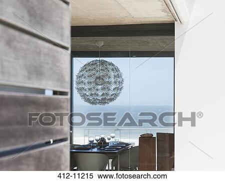 Stock Photography - Chandelier above dining table overlooking ocean. Fotosearch