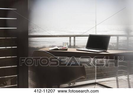 Laptop on desk in modern home office overlooking ocean View Large Photo Image Stock Photo - Laptop on desk in modern home office overlooking ocean. Fotosearch