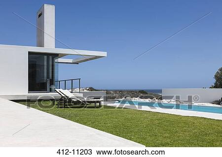 Stock Image - Lawn and lap pool along modern house. Fotosearch