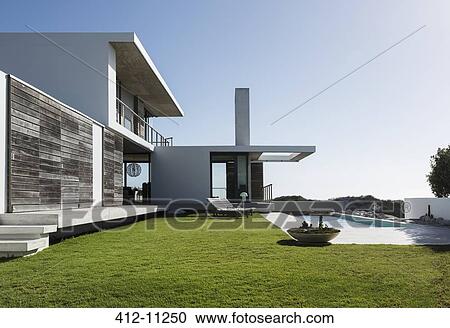 Stock Image - Lawn and lap pool outside modern house. Fotosearch