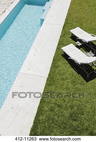 Lounge chairs on grass along lap pool View Large Photo Image Stock Image - Lounge chairs on grass along lap pool. Fotosearch