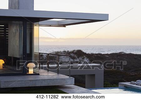Stock Image - Modern house overlooking ocean at sunset. Fotosearch