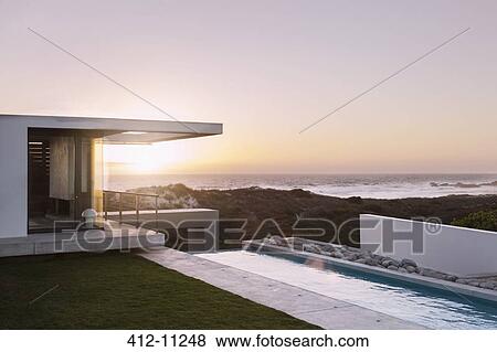 Stock Photo - Modern house overlooking ocean at sunset. Fotosearch